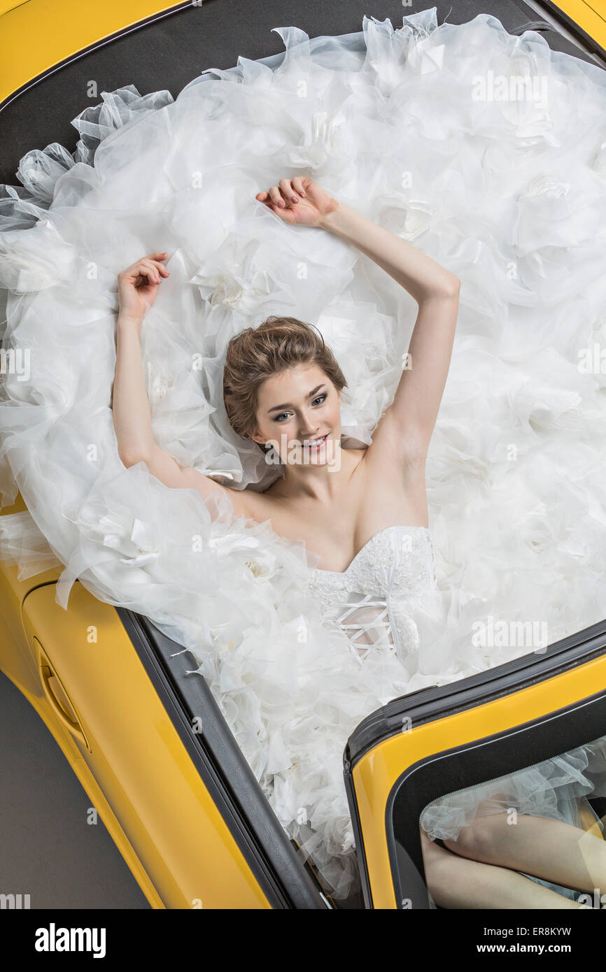 Portrait de jeune femme en robe de mariage sitting in convertible Banque D'Images