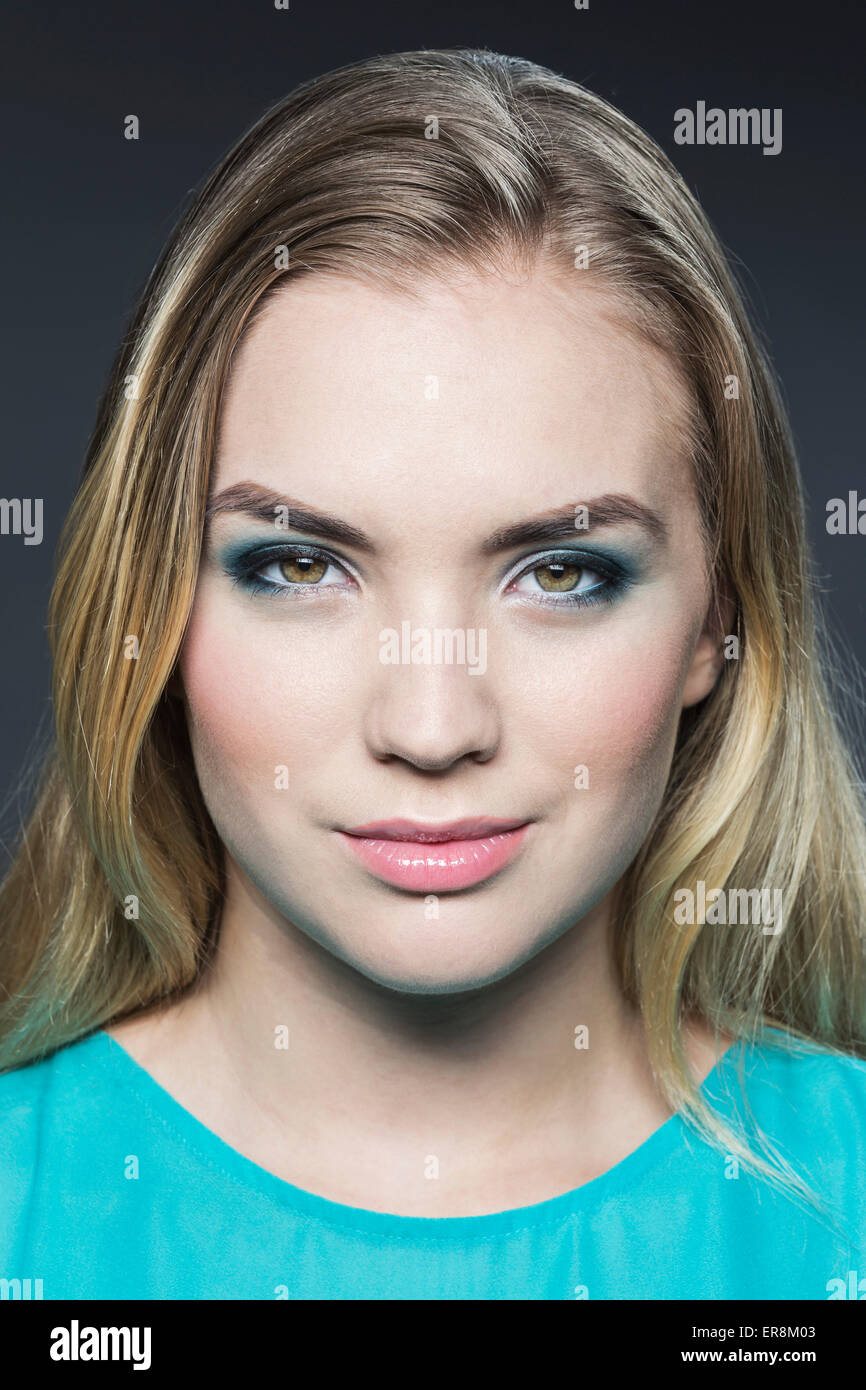 Portrait de la belle jeune femme aux cheveux blonds sur fond gris Banque D'Images