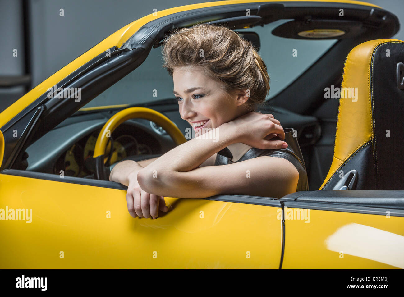 Happy woman looking away while sitting in convertible Banque D'Images