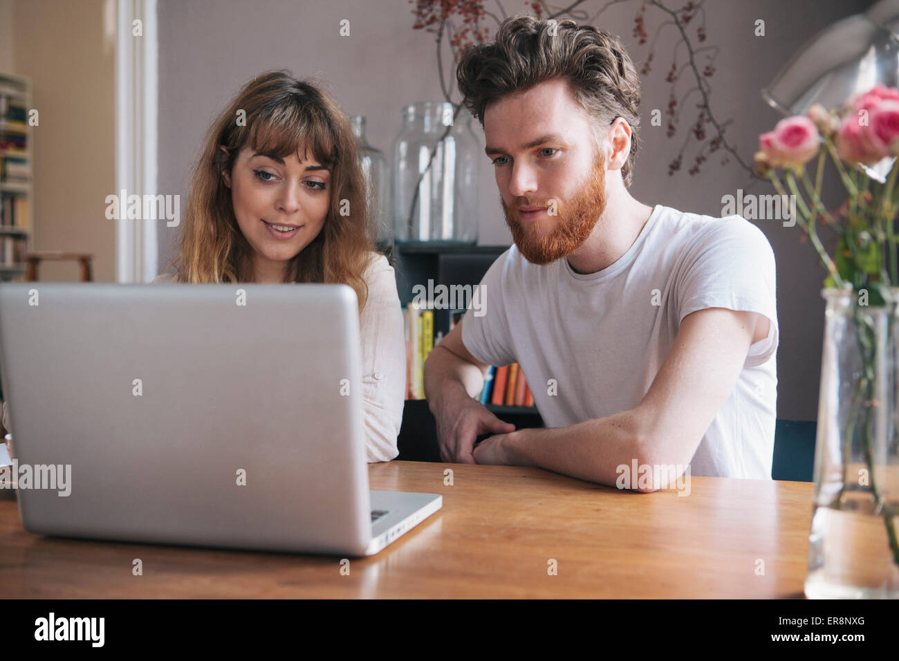 Jeune couple looking at laptop on table Banque D'Images