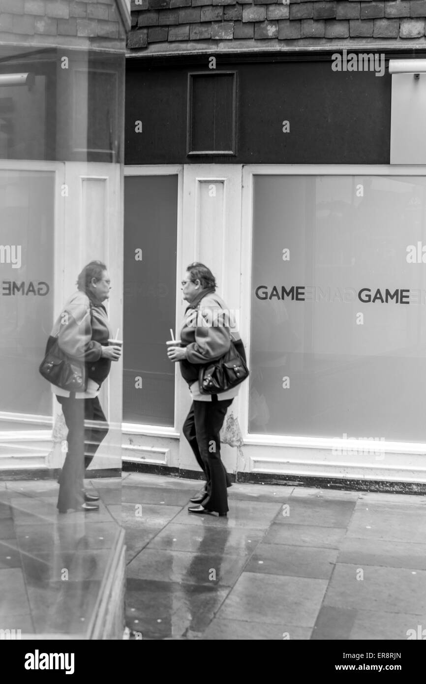 Femmes marchant sous la pluie avec reflet dans un shop à Salisbury Wiltshire Banque D'Images