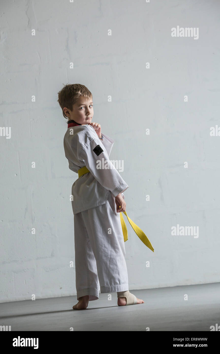 Portrait de karate boy standing contre mur blanc Banque D'Images