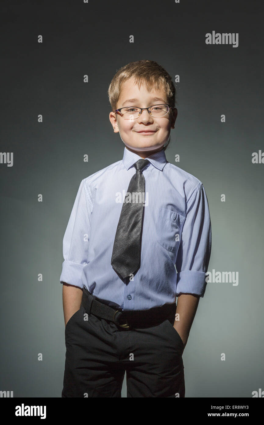Portrait de bien-habillé garçon debout contre l'arrière-plan gris Banque D'Images