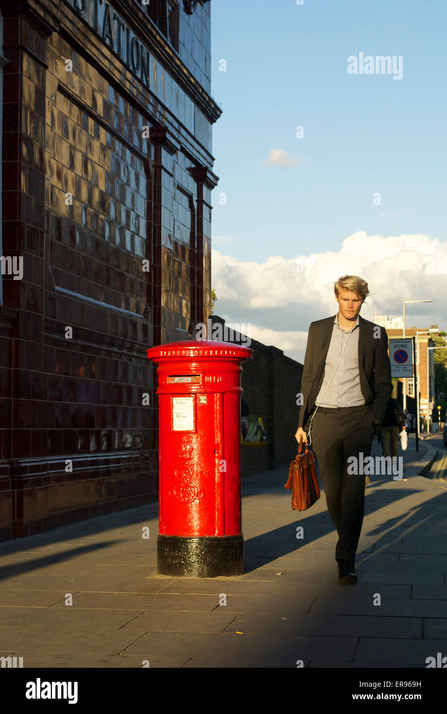 Jeune homme marchant passé UK post box in sunlit Street à Londres Photo  Stock - Alamy