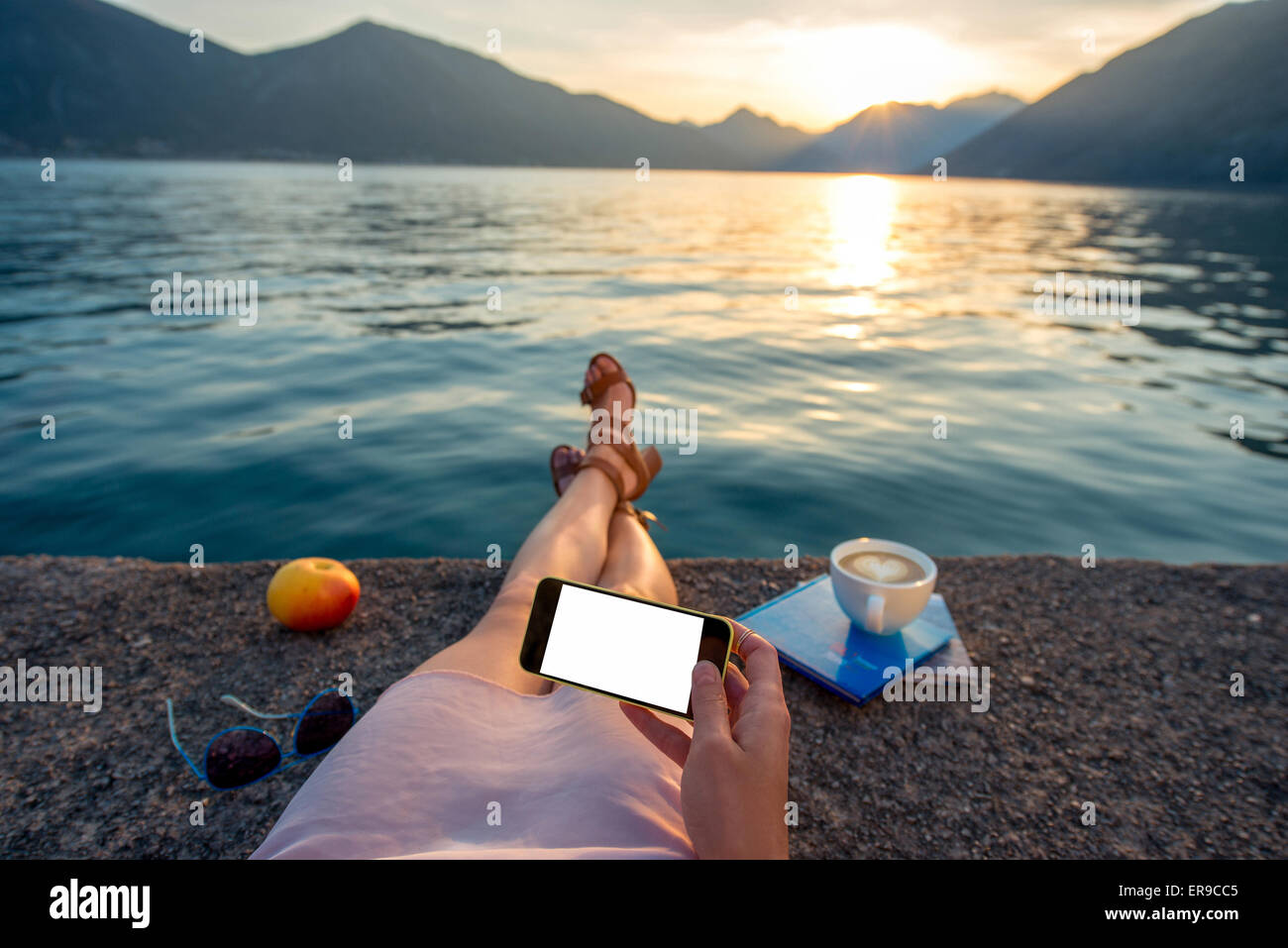 Woman holding phone lying on the pier Banque D'Images