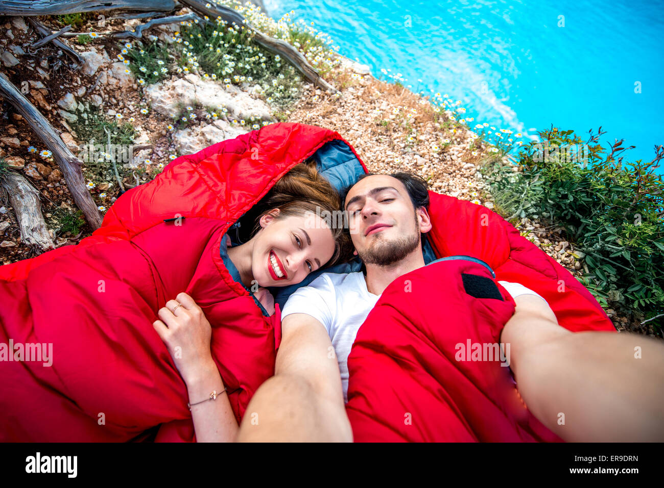 Jeune couple dans des sacs de couchage près de la mer Banque D'Images