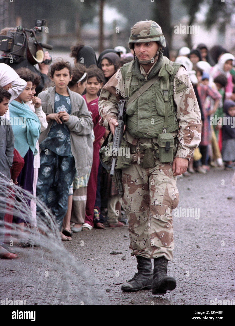 23 mars 1991 un soldat de l'armée américaine garde une ligne ordonnée d'Irakiens déplacés, faisant la queue pour la nourriture et les boissons près de Safwan dans le sud de l'Irak. Banque D'Images