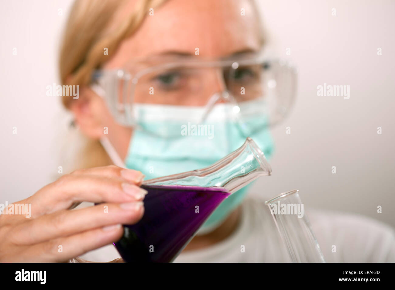 Chimiste s'incline du liquide d'un fiole dans un tube à essai Banque D'Images