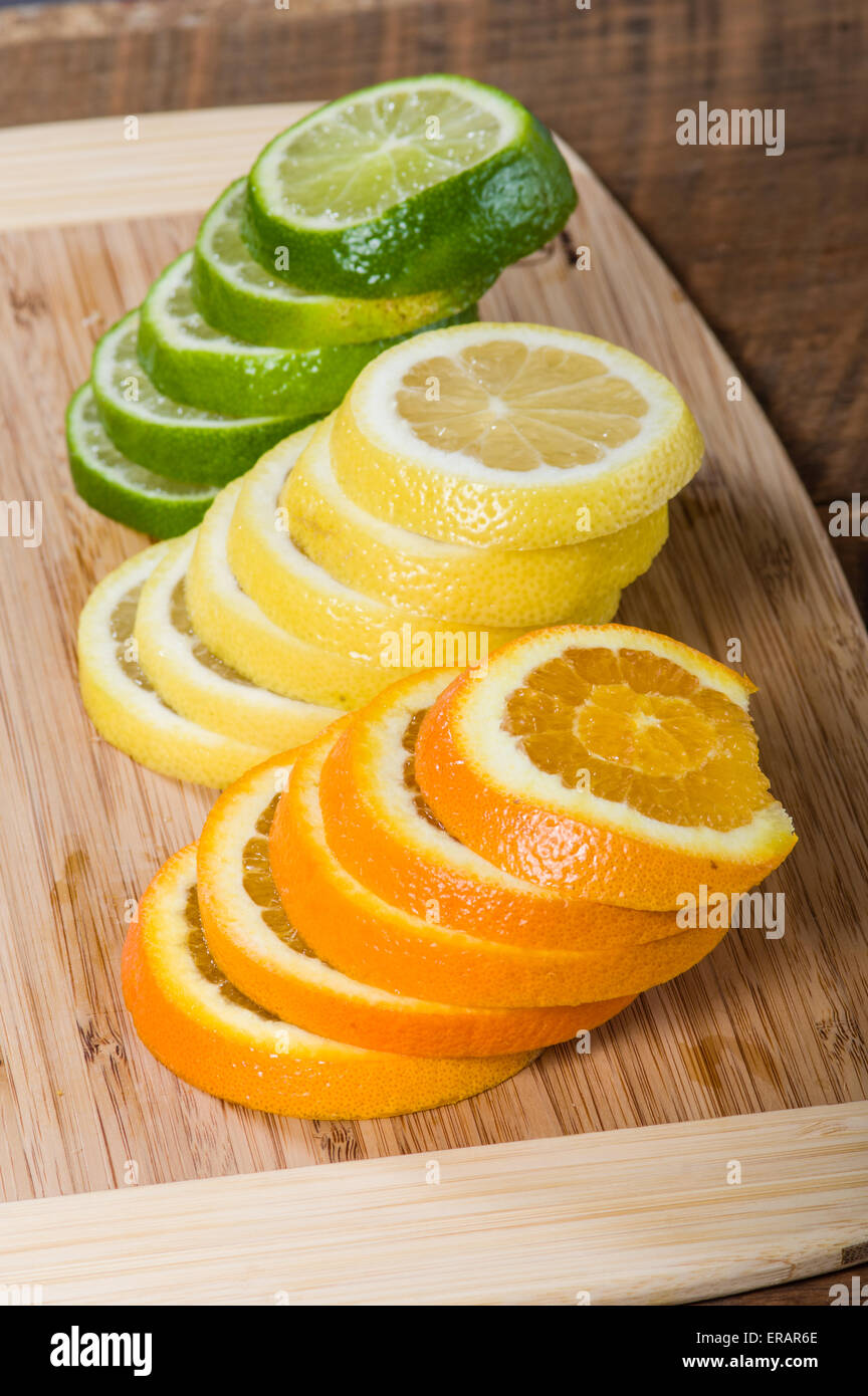 Des piles de citron, de limette et de rondelles d'orange sur une planche à découper Banque D'Images