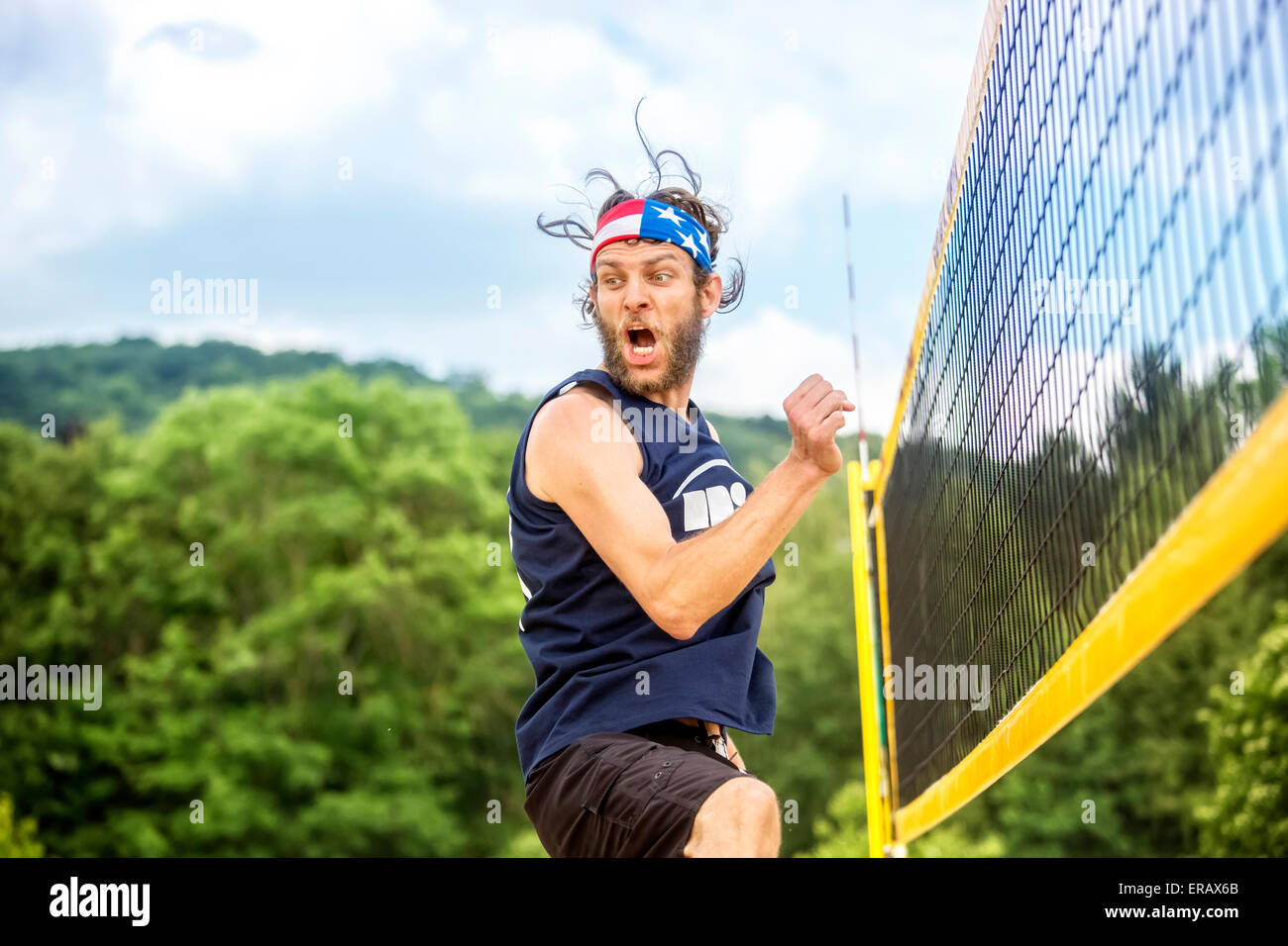 Naturels beachvolley ball player avec stars and stripes bandana célèbre son succès jeu émotionnel. Banque D'Images