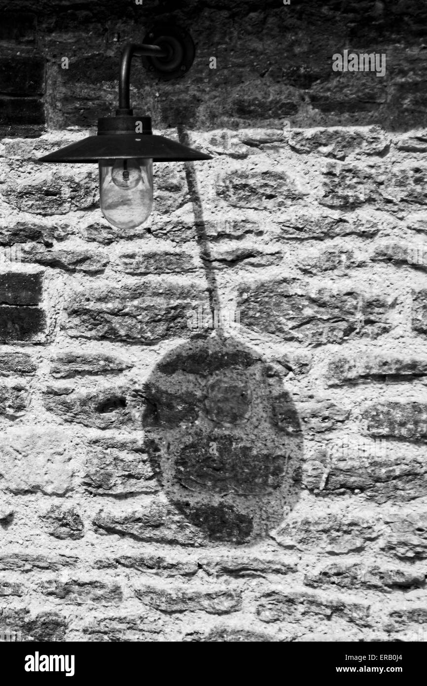 Lampe ombre créée par l'extérieur sur mur de pierre, sur un bâtiment de ferme dans le Somerset. Banque D'Images