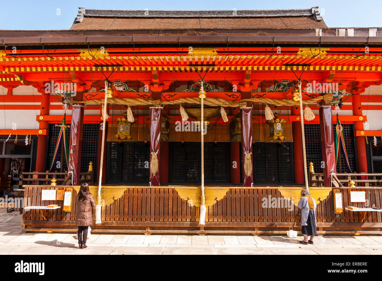 Les gens priaient devant le vermilion Gion-zukuri, le principal hall du célèbre sanctuaire Shinto Yasaka à Kyoto. Printemps, soleil éclatant Banque D'Images