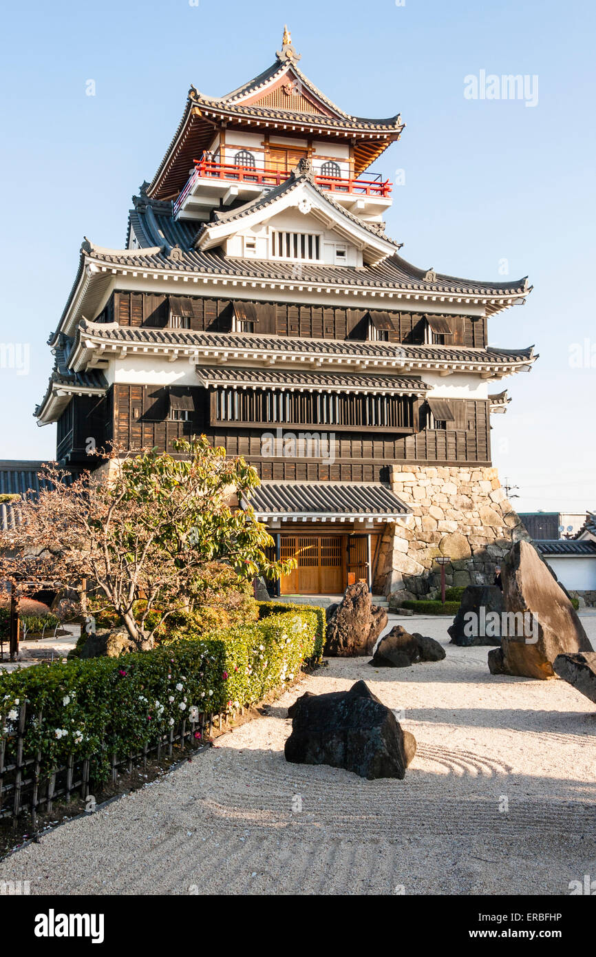 Japon, Nagoya, château reconstruit de Kiyosu, avec un château de style Borogata garder le soleil contre le ciel bleu clair. Au premier plan, un jardin japonais en pierre. Banque D'Images