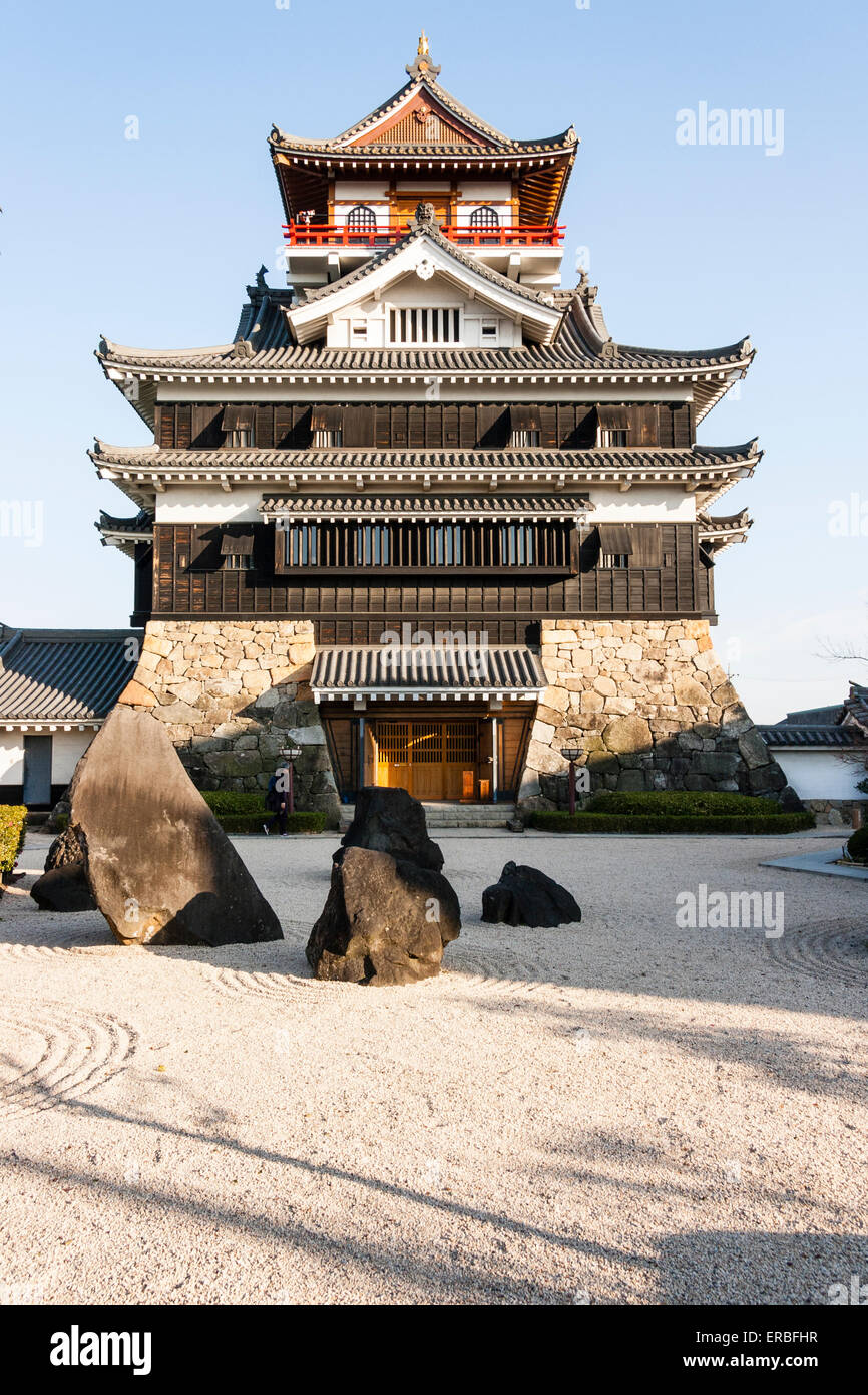 Japon, Nagoya, château reconstruit de Kiyosu, avec un château de style Borogata garder le soleil contre le ciel bleu clair. Au premier plan, un jardin japonais en pierre. Banque D'Images