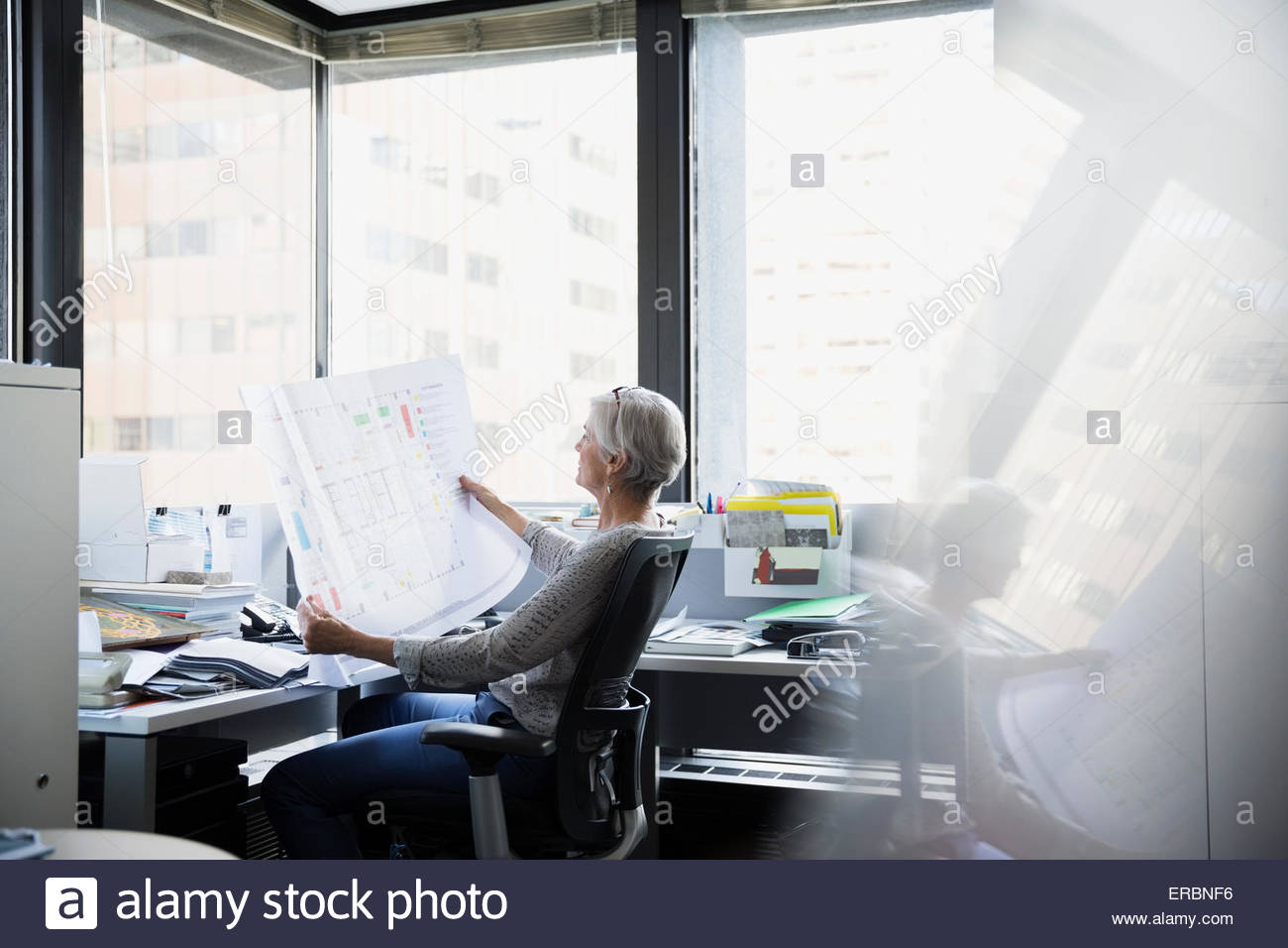 Architect reviewing blueprints at office desk Banque D'Images