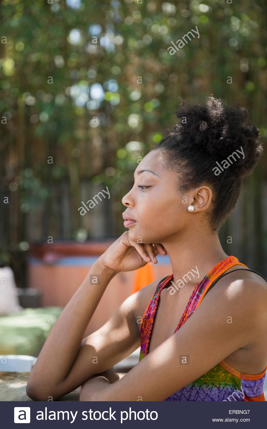 Profil de pensive woman sitting on patio Banque D'Images