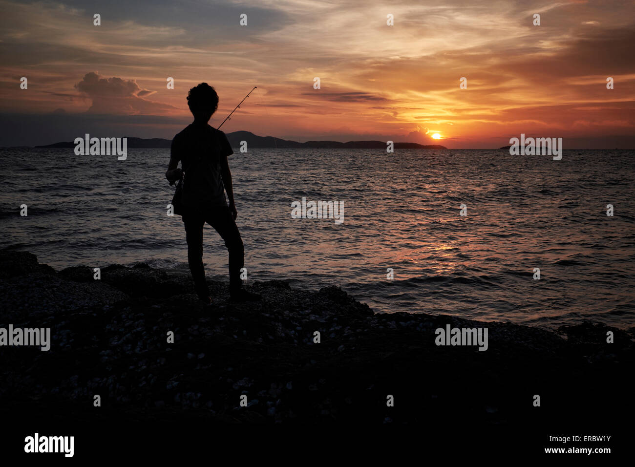 Pêcheur solitaire contre l'établissement. Banque D'Images