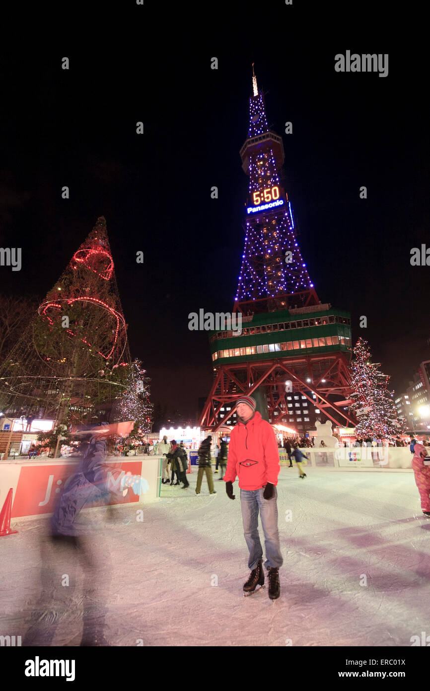 Les familles et les couples profiter de la patinoire au pied de la tour de télévision de Odori Park au cours de l'hiver Snow Festival, Sapporo, Japon. Banque D'Images