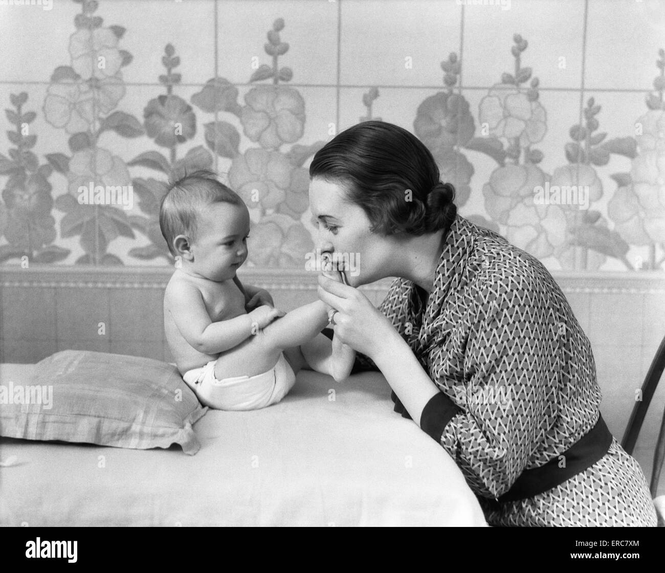 1930 FEMME Mère embrassant les pieds de bébés Banque D'Images