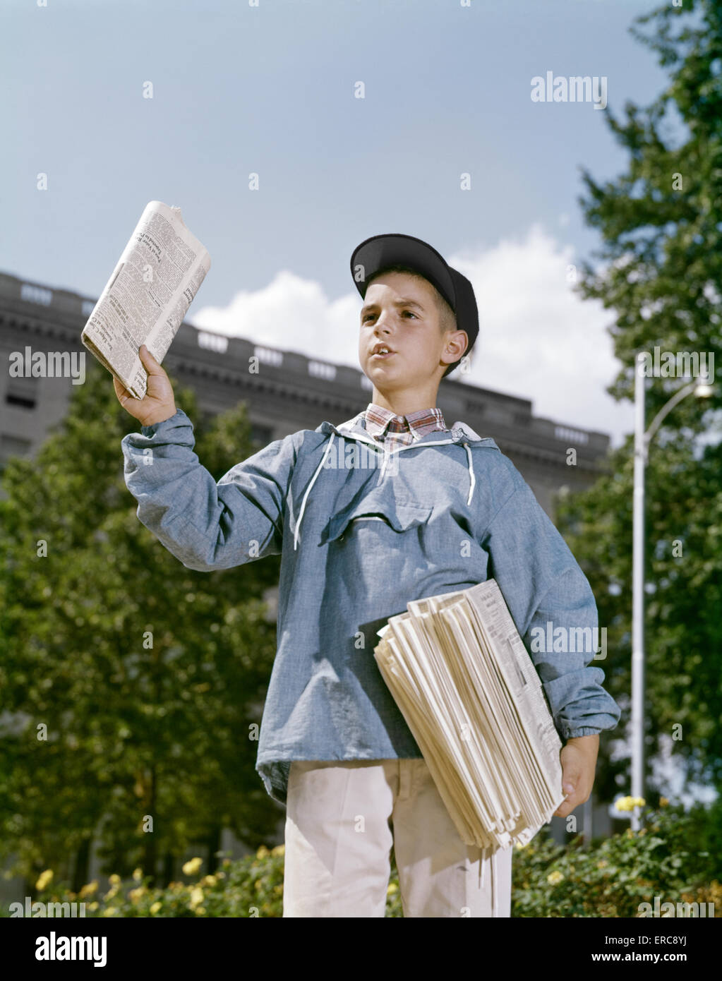 1960 garçon Vente de journaux portant une casquette veste bleue Banque D'Images