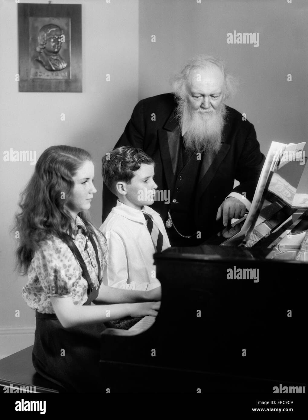 Années 1930 Années 1940 Garçon Fille assis au piano avec l'homme âgé LES REGARDER JOUER L'ENSEIGNANT Banque D'Images