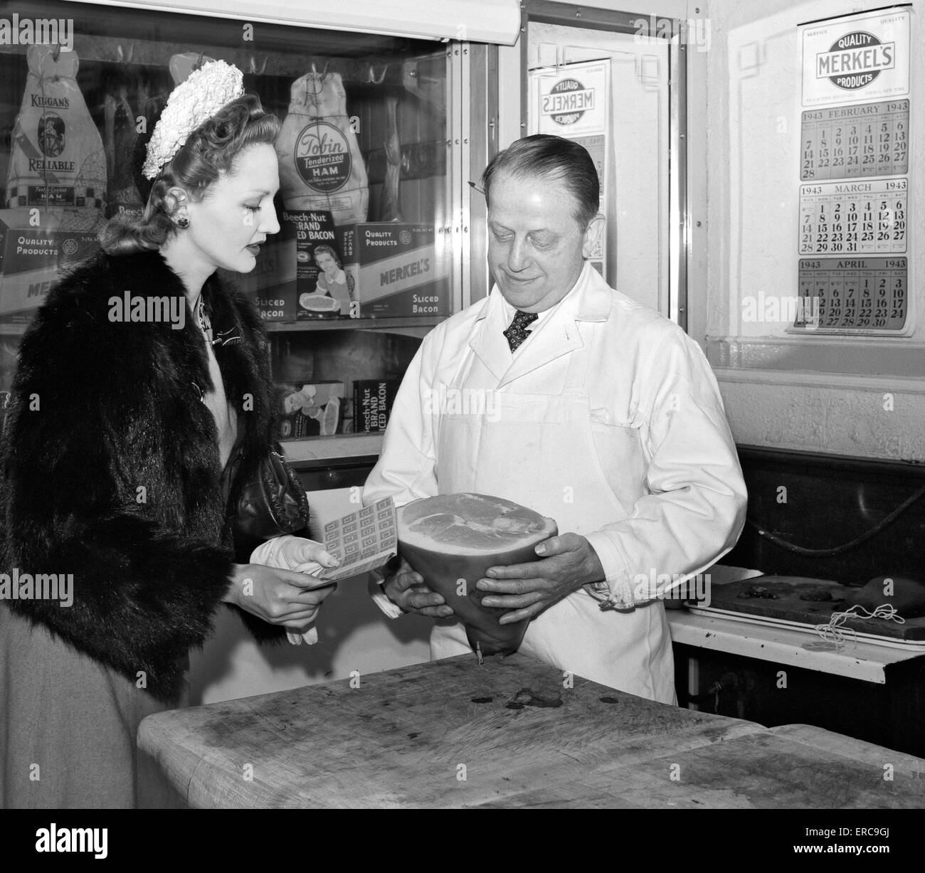 1940 CLIENT FEMME MONTRANT SON POINT DE RATIONS LIVRE À BUTCHER, AU MEAT MARKET NEW YORK CITY NEW YORK USA Banque D'Images