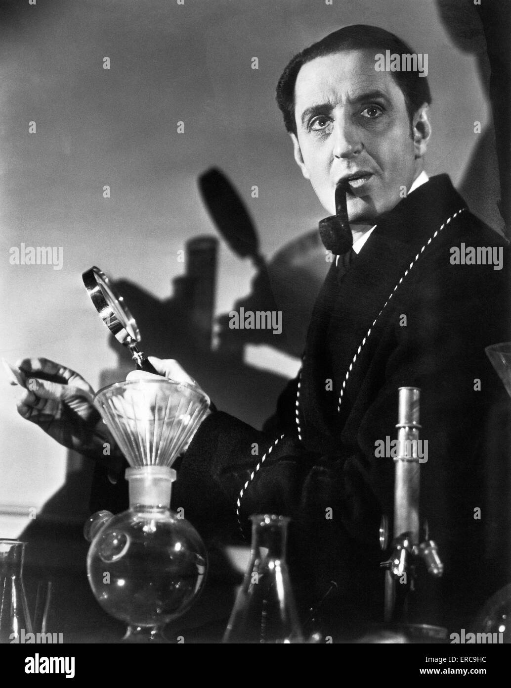 Années 1930 Années 1940 L'ACTEUR Basil Rathbone comme détective CONSULTANT SHERLOCK HOLMES AVEC TUYAU LOUPE PAR AUTEUR Arthur Conan Doyle Banque D'Images