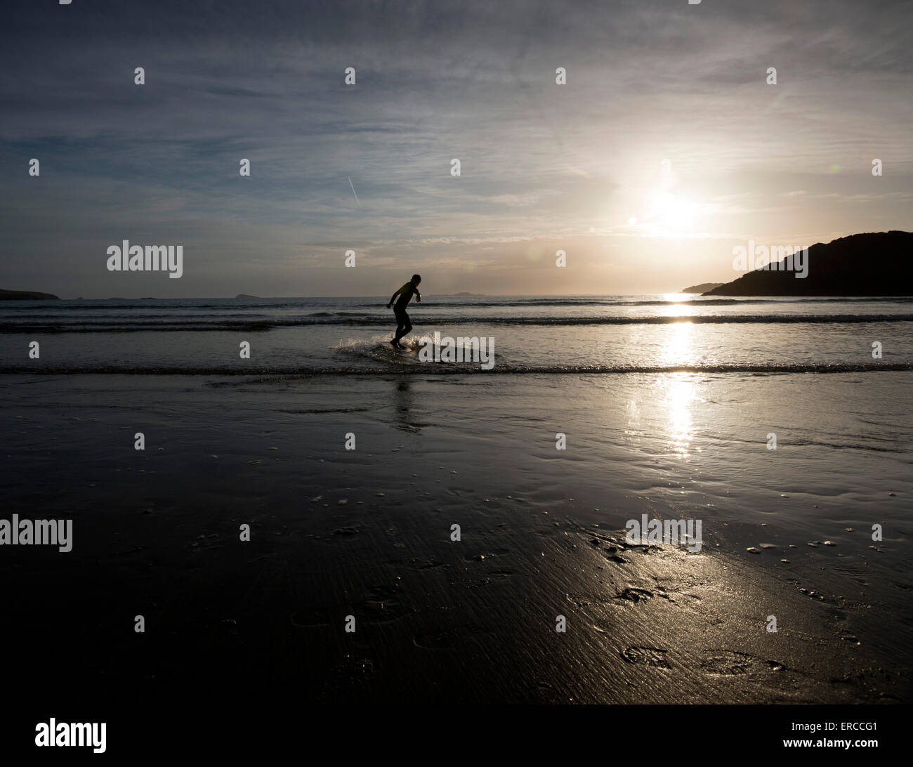 Un jeune garçon skimboarding Whitesands Beach au coucher du soleil à St Davids, Pembrokeshire Wales Banque D'Images