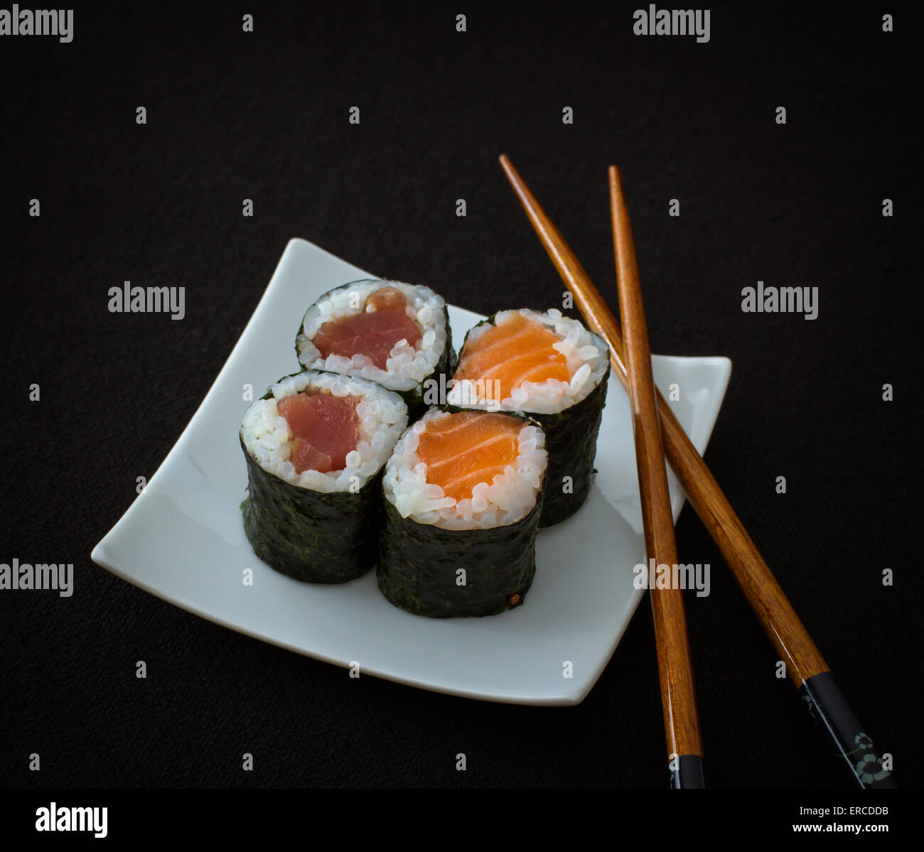 Saumon, thon maki sushi et chopstick sur noir, vue du dessus Banque D'Images