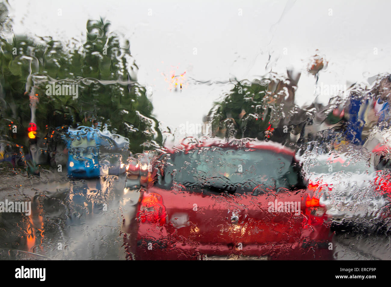 Vu à travers les gouttes d'eau sur le pare-brise de voiture sur des voitures dans la circulation Banque D'Images