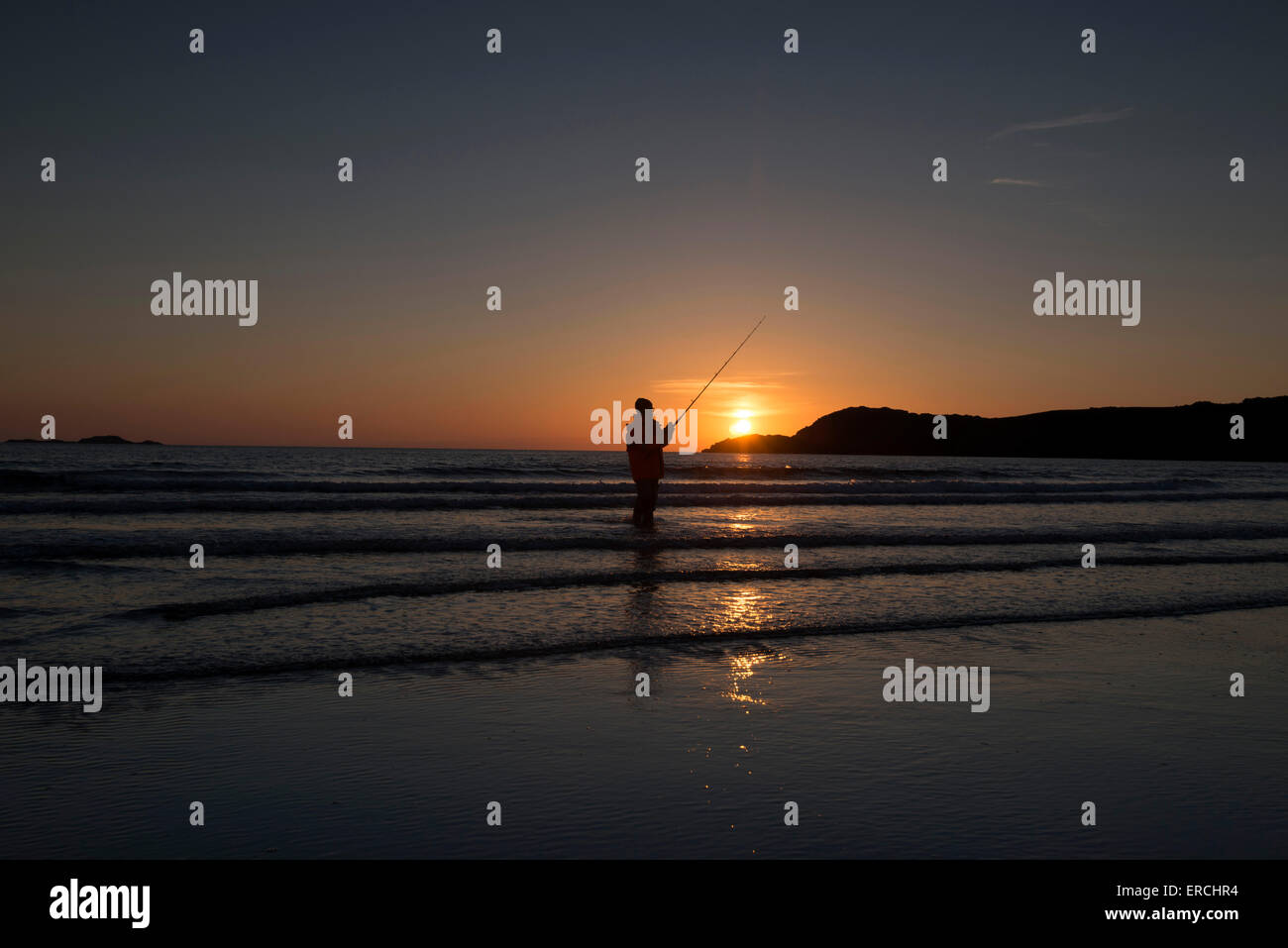 Silhouette d'un pêcheur au coucher du soleil, le Whitesands Beach à St Davids, Pembrokeshire Wales Banque D'Images