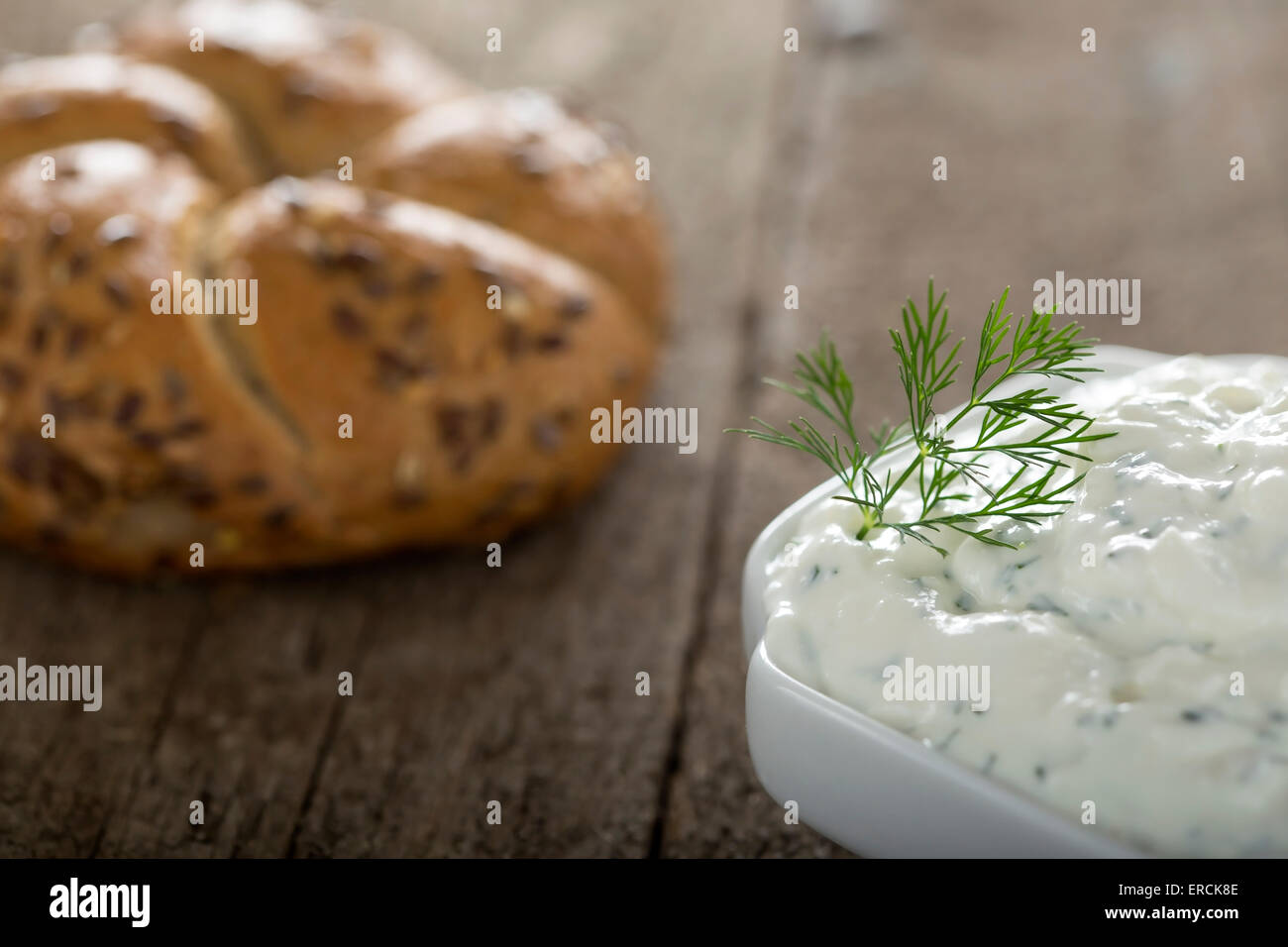 Bol de sauce au fromage frais sur fond de bois avec un bagel en arrière-plan Banque D'Images