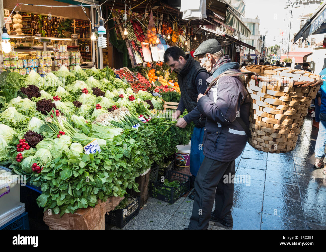 Un porteur s'entretient à un kiosque de légumes au marché de rue de Kadikoy, Istanbul, Turquie. Banque D'Images