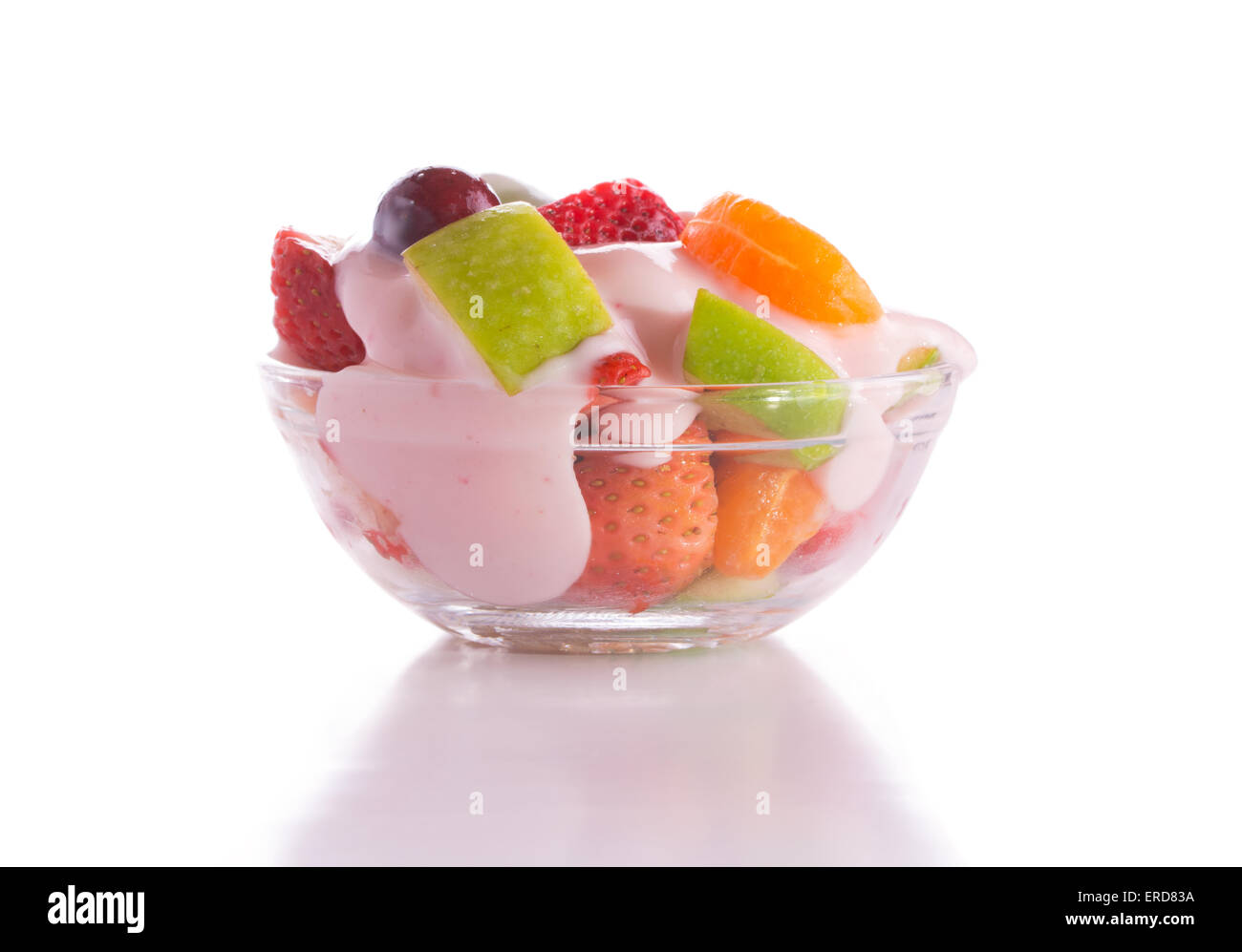 Petit déjeuner nutritif avec salade de fruit rose garni de yogourt aux fraises dans un bol en verre, sur fond blanc Banque D'Images
