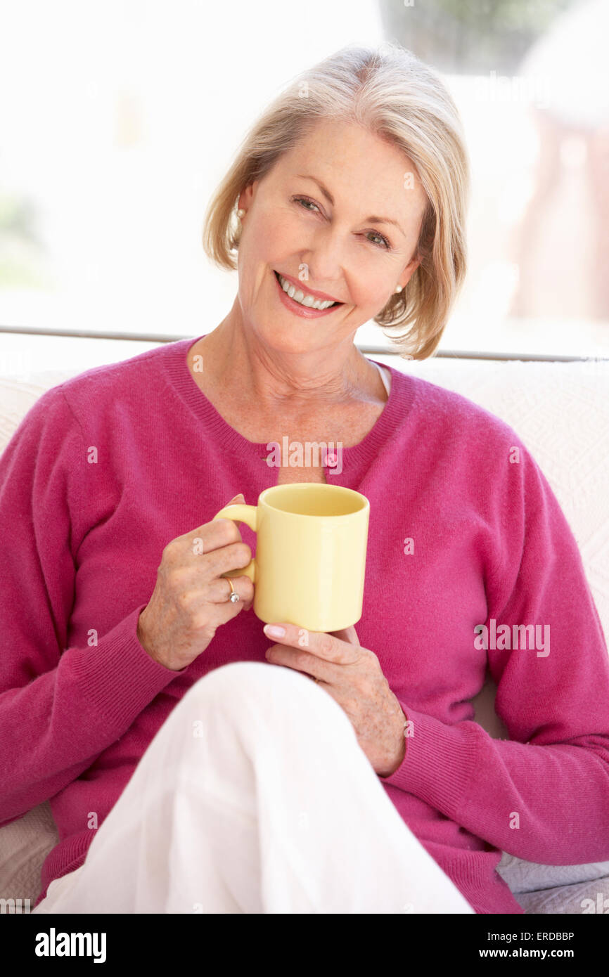 Senior Woman Relaxing At Home avec boisson chaude Banque D'Images
