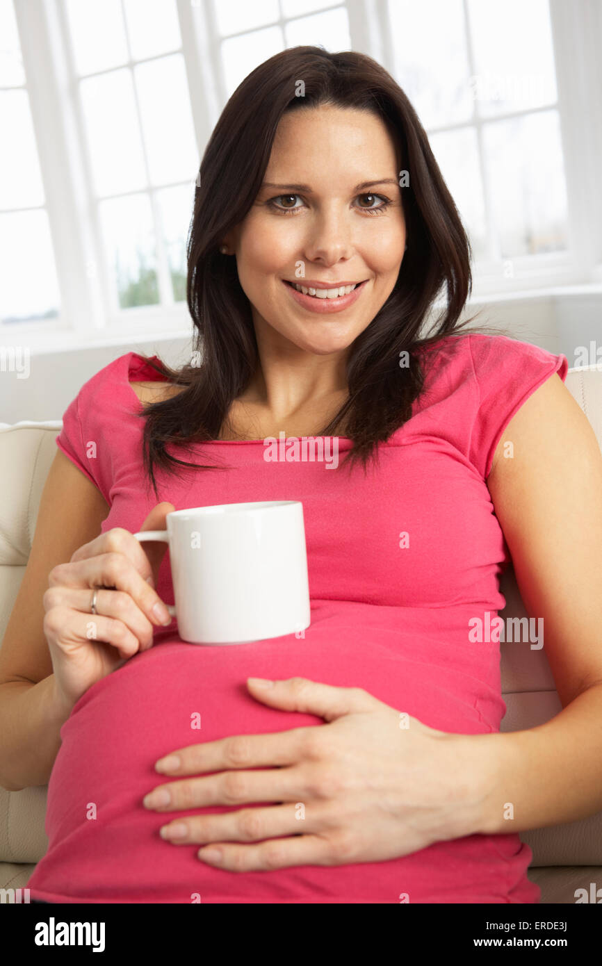 Femme enceinte de boire une boisson chaude à la maison Banque D'Images