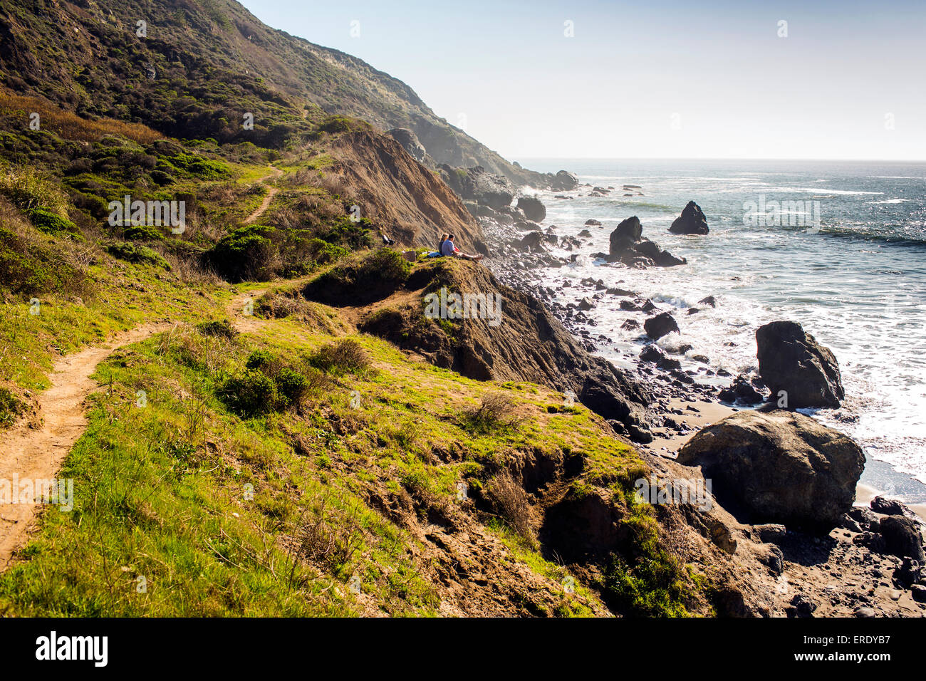 Des gens assis sur le sentier littoral rocheux près de ocean Banque D'Images