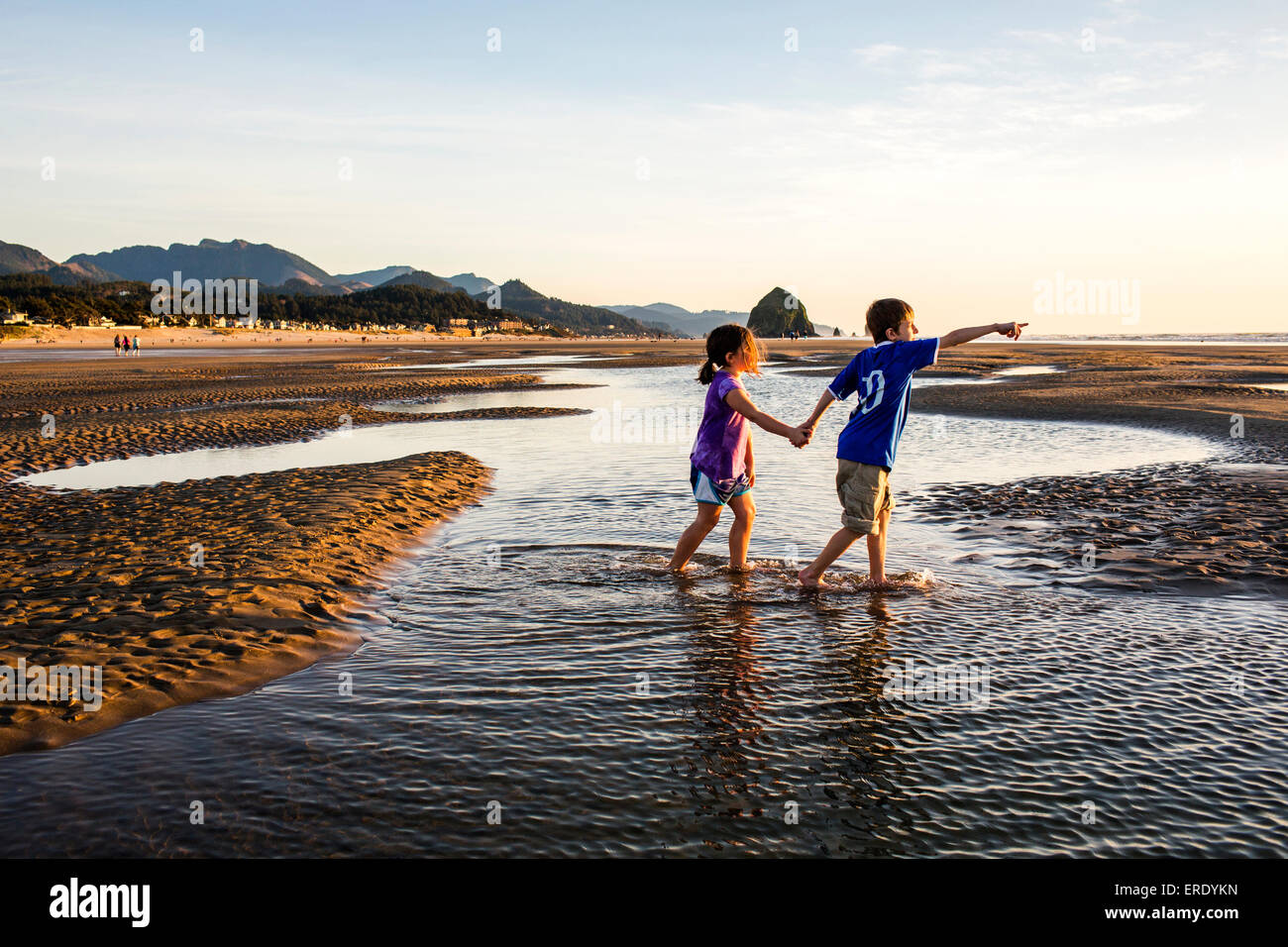 La marche des enfants de race blanche dans les mares d'eau sur la plage, Cannon Beach, Oregon, United States Banque D'Images
