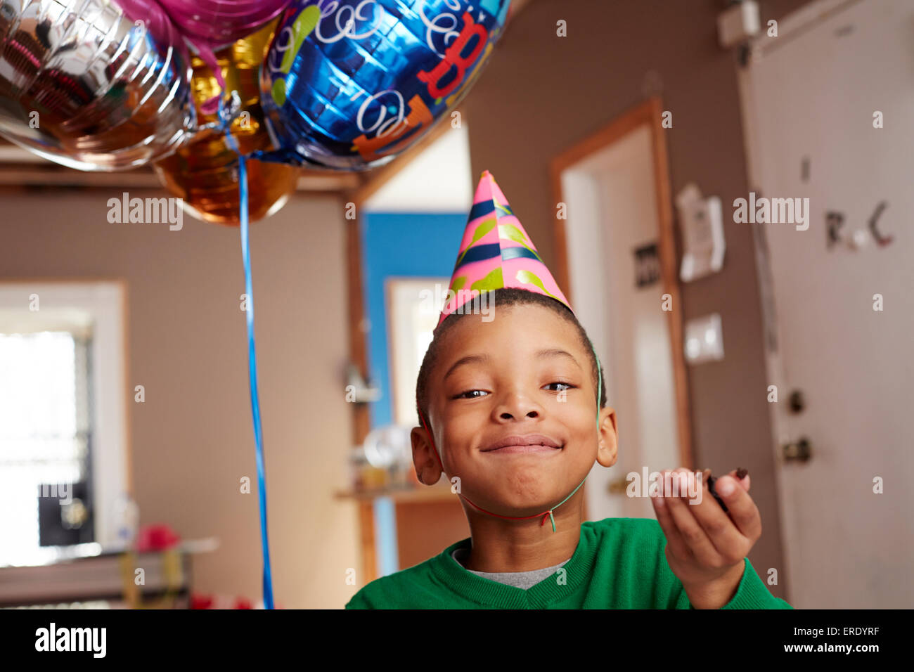 Black Boy wearing party hat holding balloons Banque D'Images