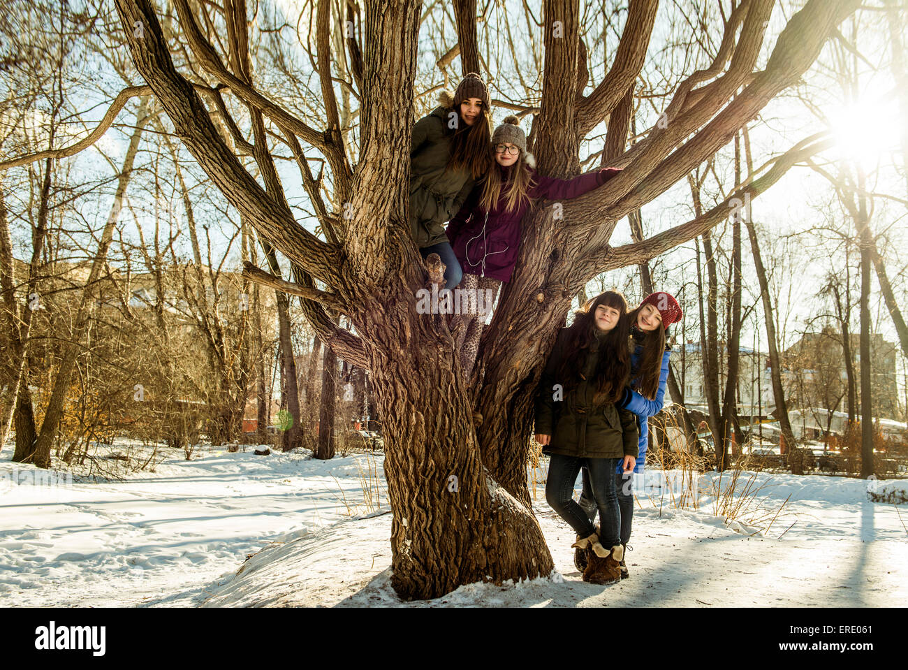 Caucasian girls smiling at tree in snowy field Banque D'Images