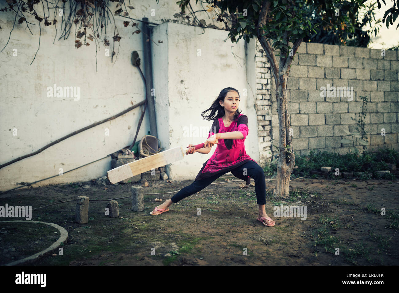 Mixed Race girl playing cricket près de wall Banque D'Images