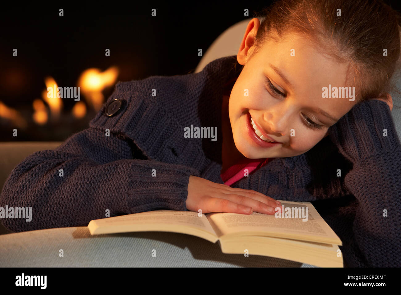 Portrait 7 ans, fille de la lecture à la lueur du feu Banque D'Images