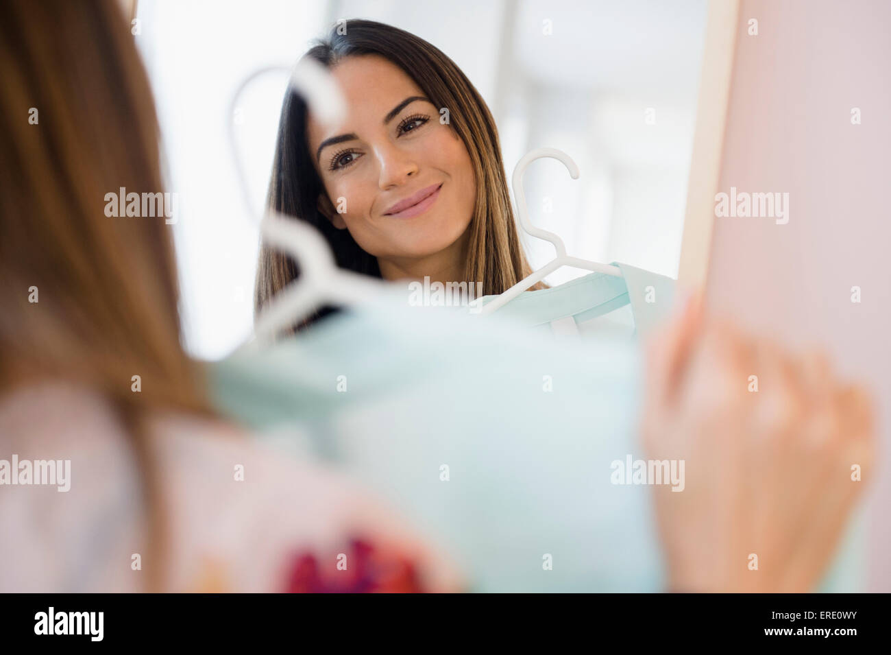 Caucasian woman admiring shirt dans mirror Banque D'Images
