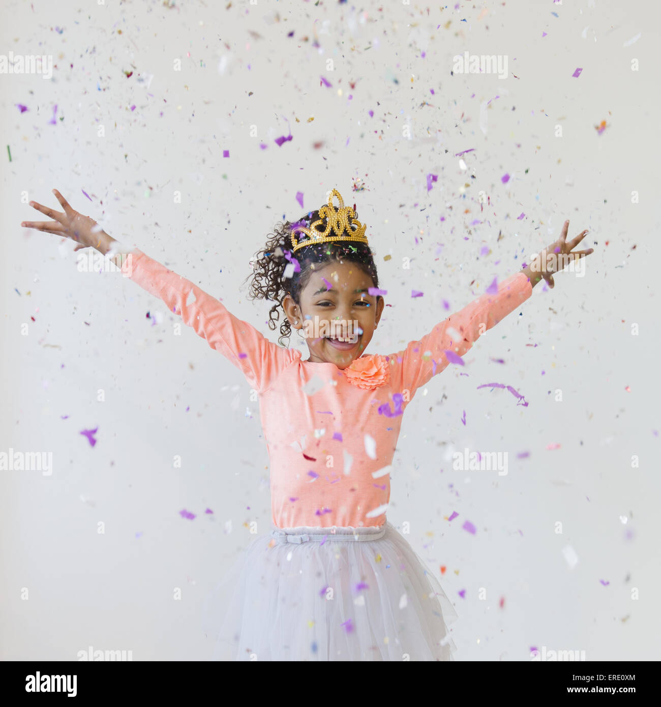 Mixed Race girl wearing tiara throwing confetti Banque D'Images