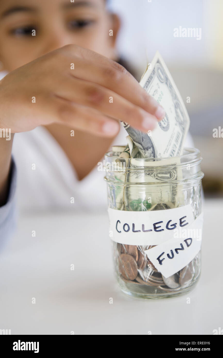 Mixed Race girl d'économiser de l'argent en college fund jar Banque D'Images