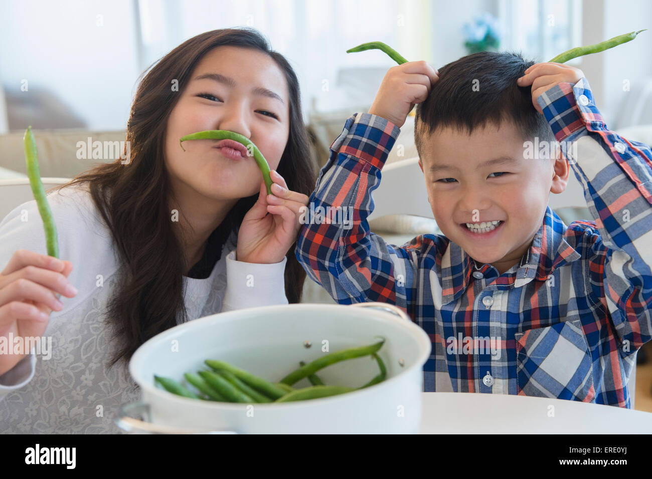 Frère et soeur asiatique jouant avec des légumes Banque D'Images