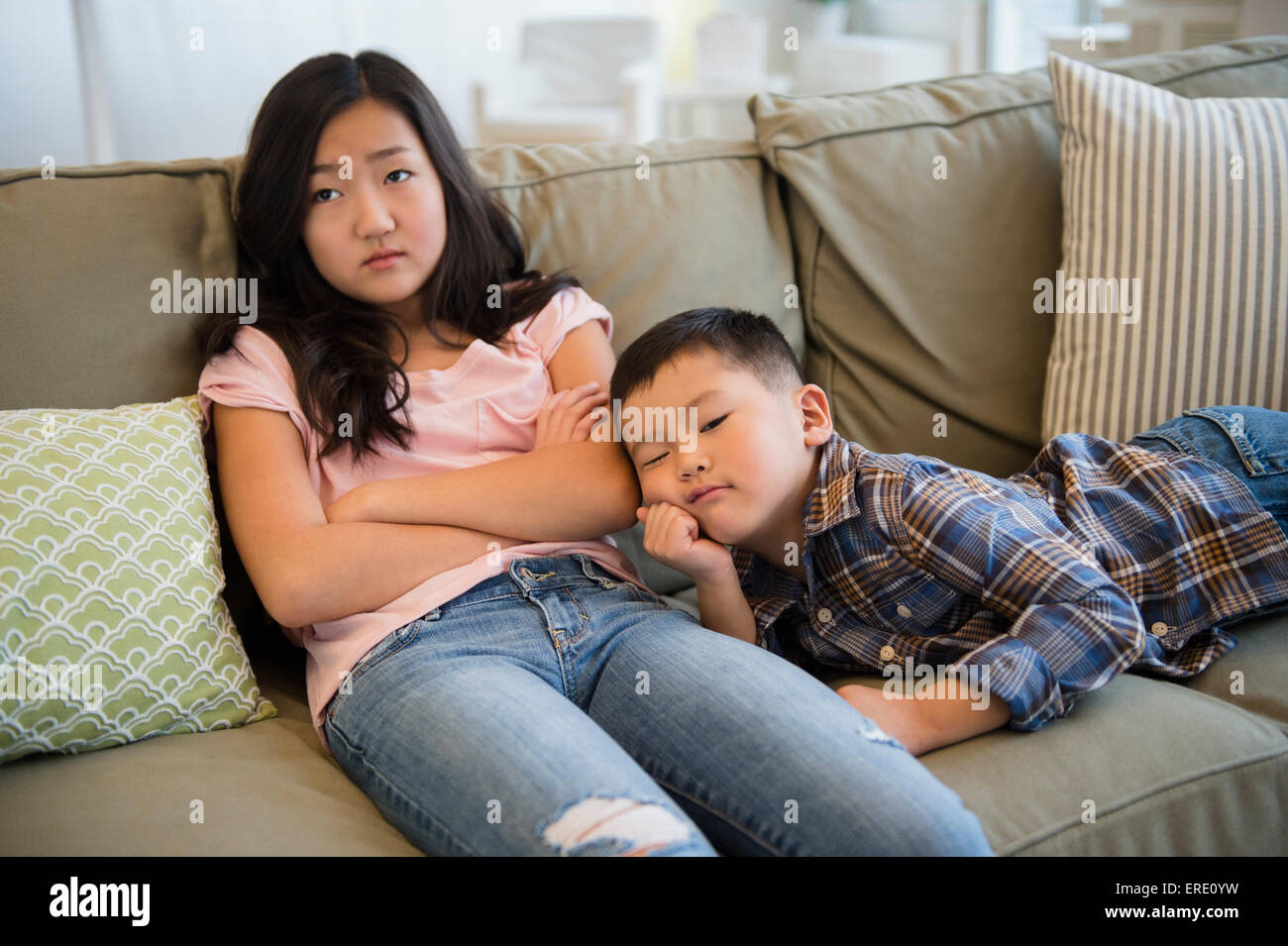 Bored Asian frère et sœur relaxing on sofa Banque D'Images