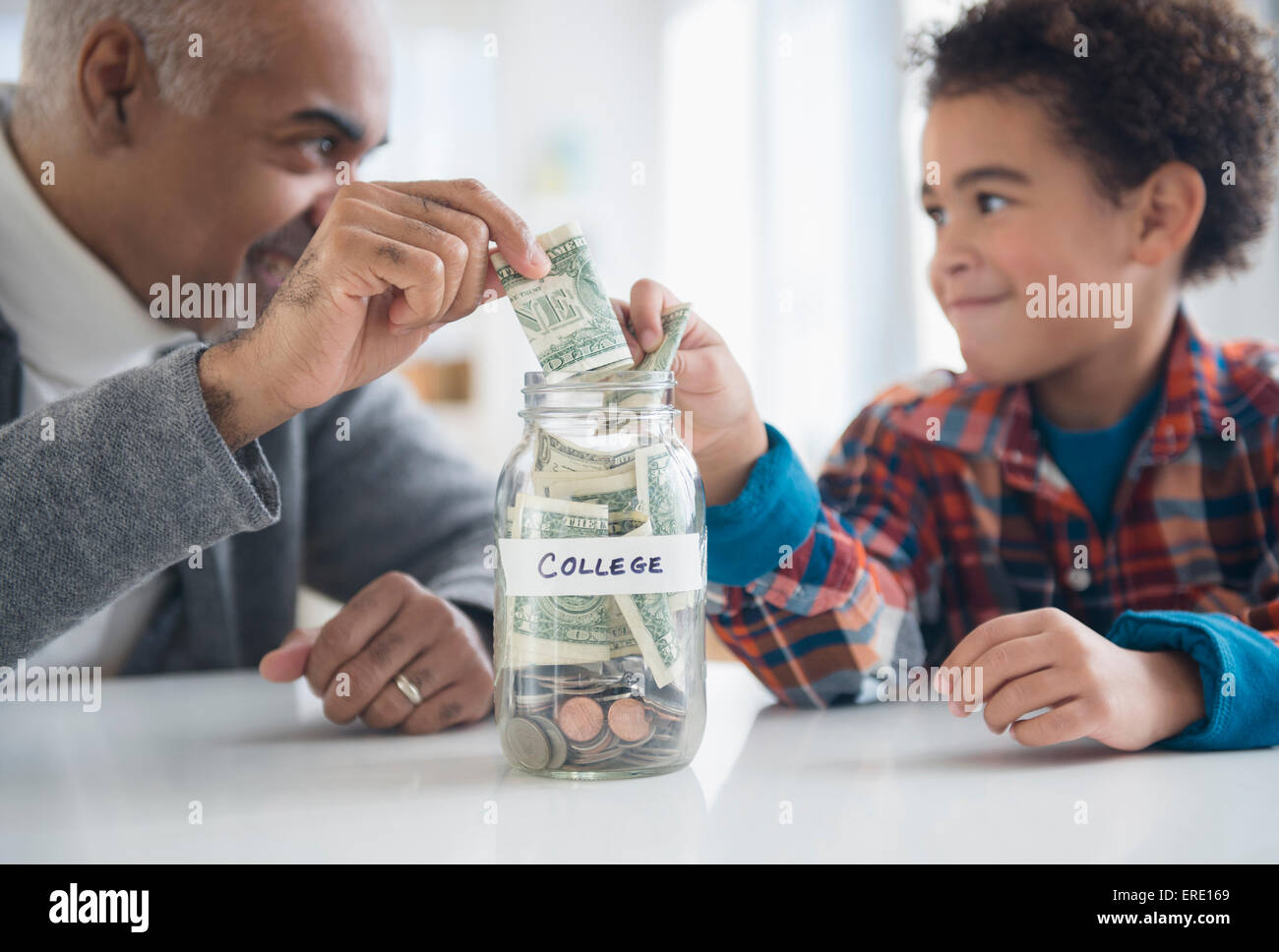 Mixed Race grand-père et petit-fils d'économiser de l'argent dans la région de college fund jar Banque D'Images