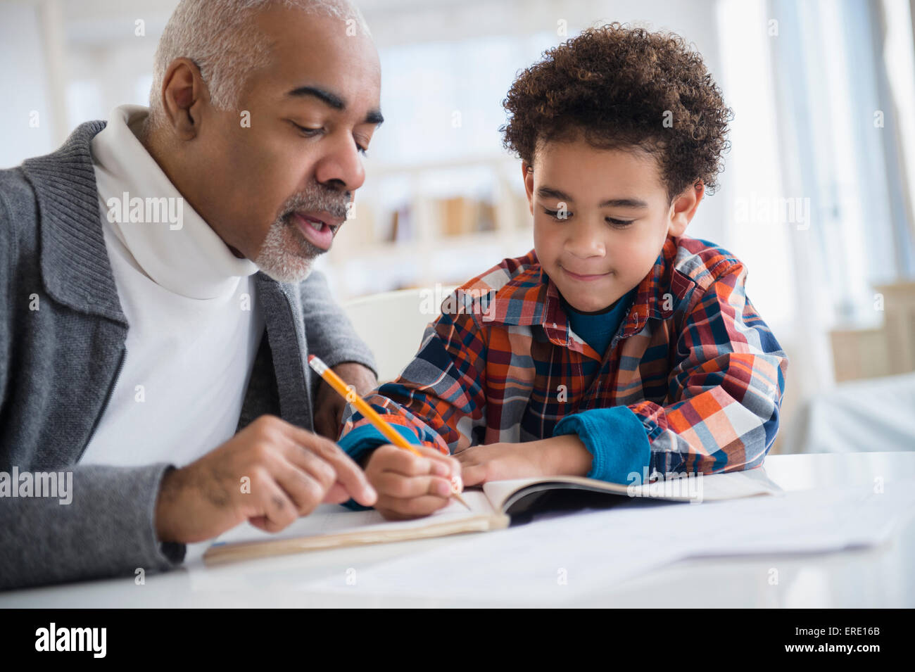 Mixed Race grand-père petit-fils aidant à faire ses devoirs Banque D'Images