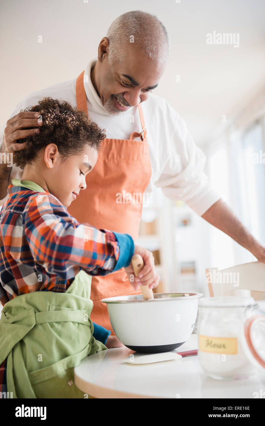 Mixed Race grand-père et petit-fils baking in kitchen Banque D'Images